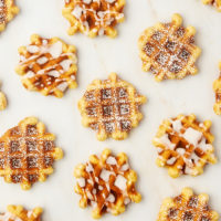 overhead view of waffle cookies, some topped with powdered sugar and some with a simple glaze