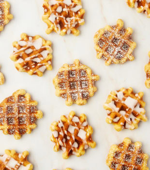 overhead view of waffle cookies, some topped with powdered sugar and some with a simple glaze