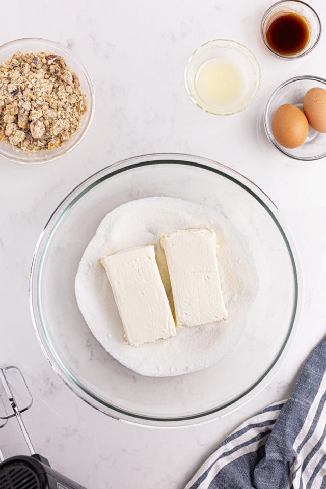 overhead view of cream cheese and sugar in a glass mixing bowl