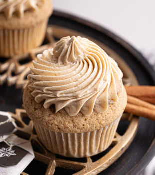 a chai spice cupcake on a cake stand surrounded by more cupcakes