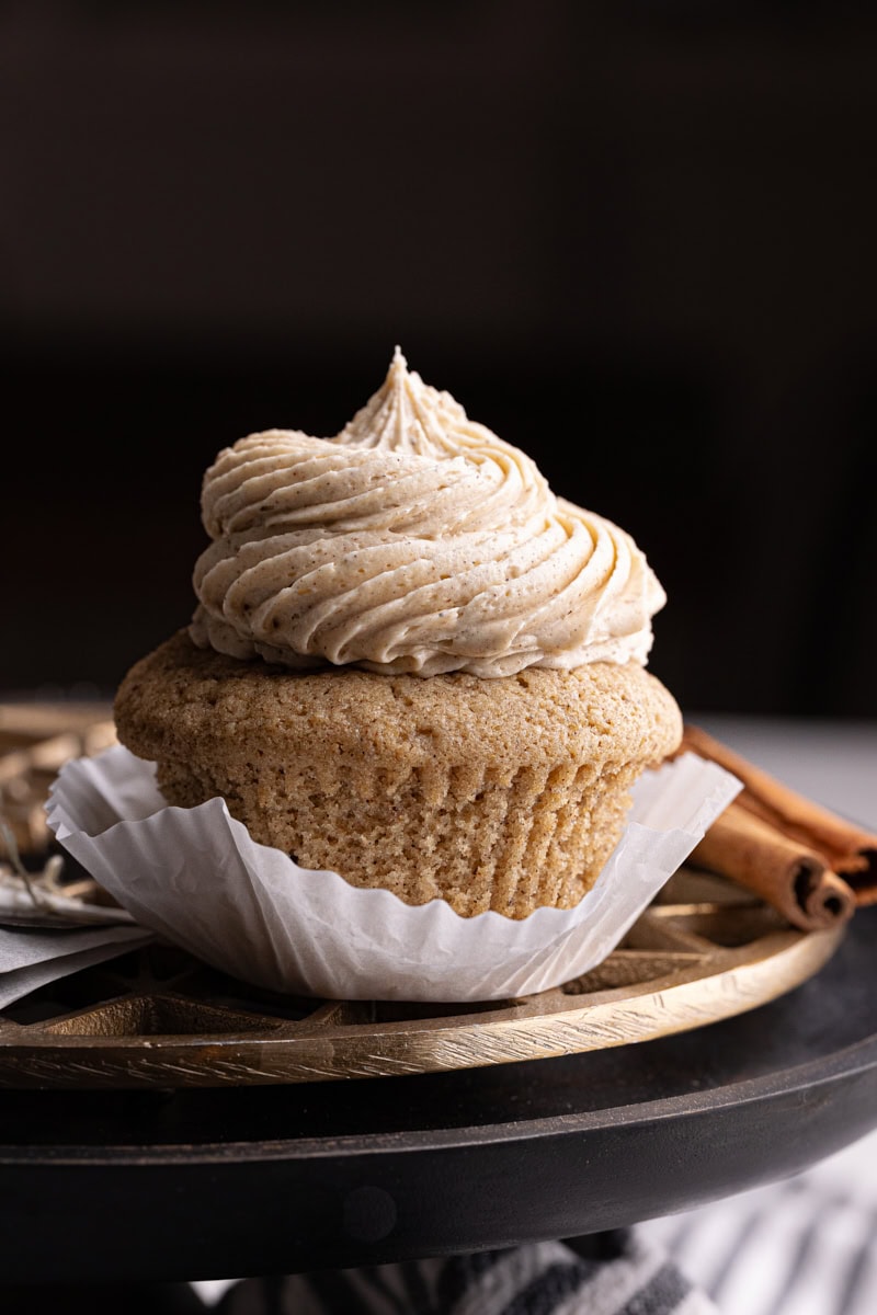 a partially unwrapped chai spice cupcake on a brass and black cake stand