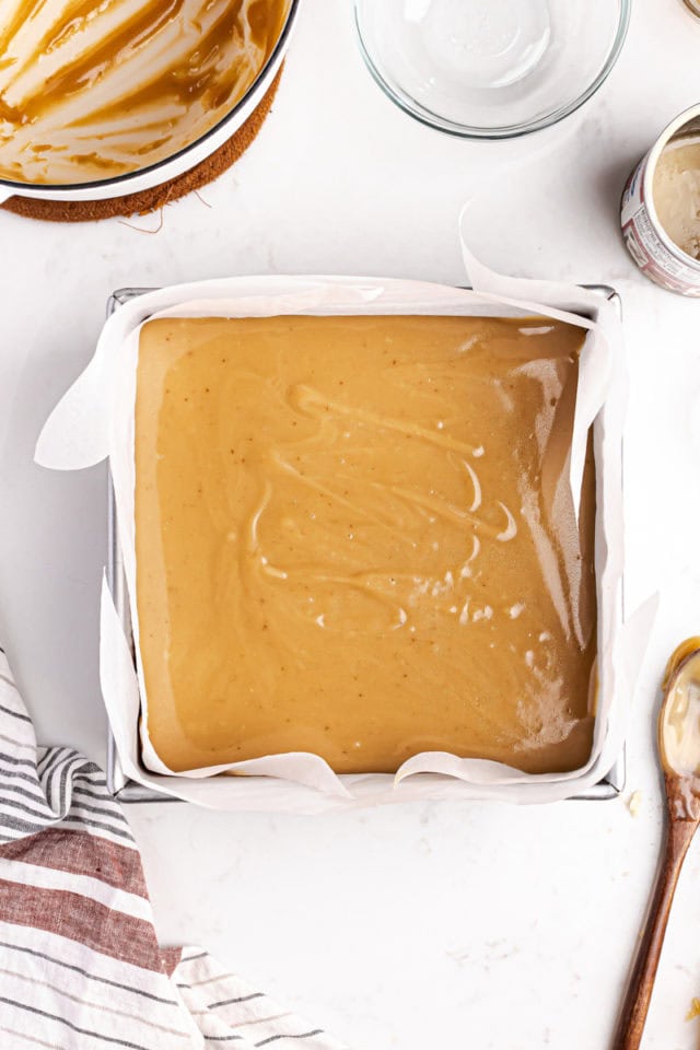 overhead view of caramel spread on top of shortbread in a square pan