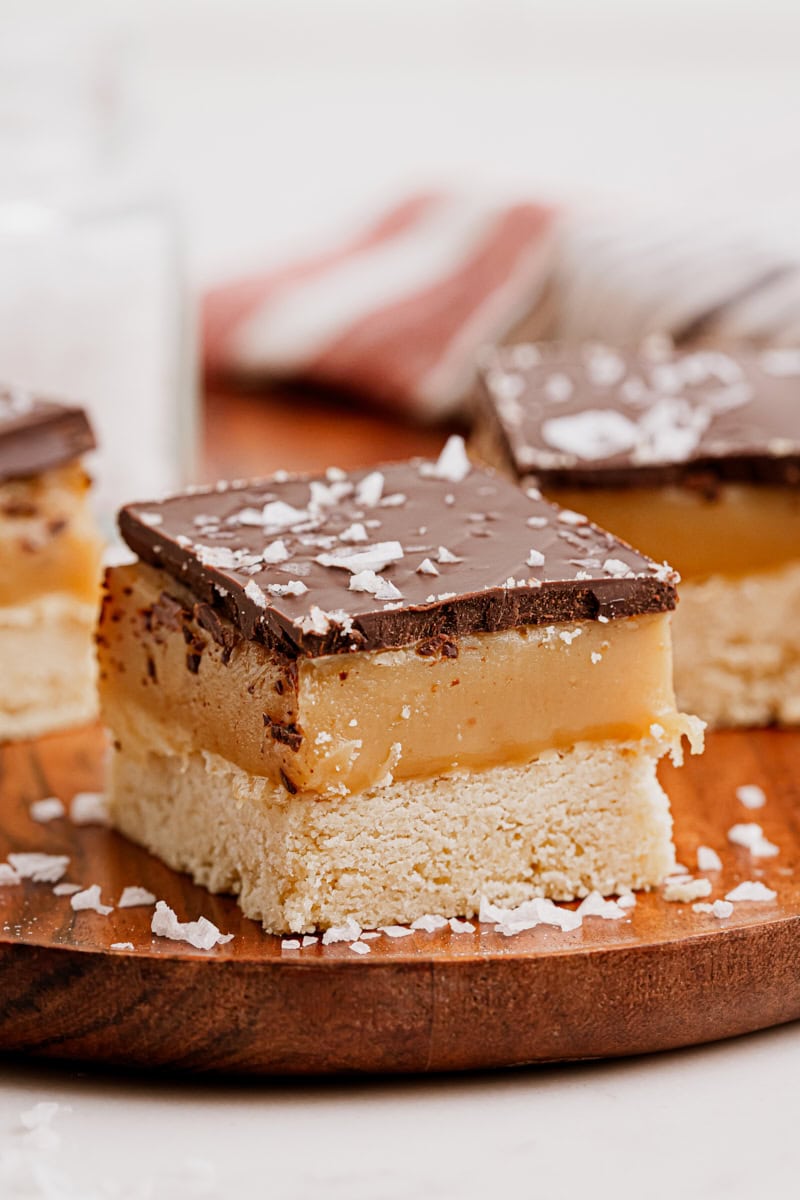 a millionaire shortbread bar on a wooden cutting board