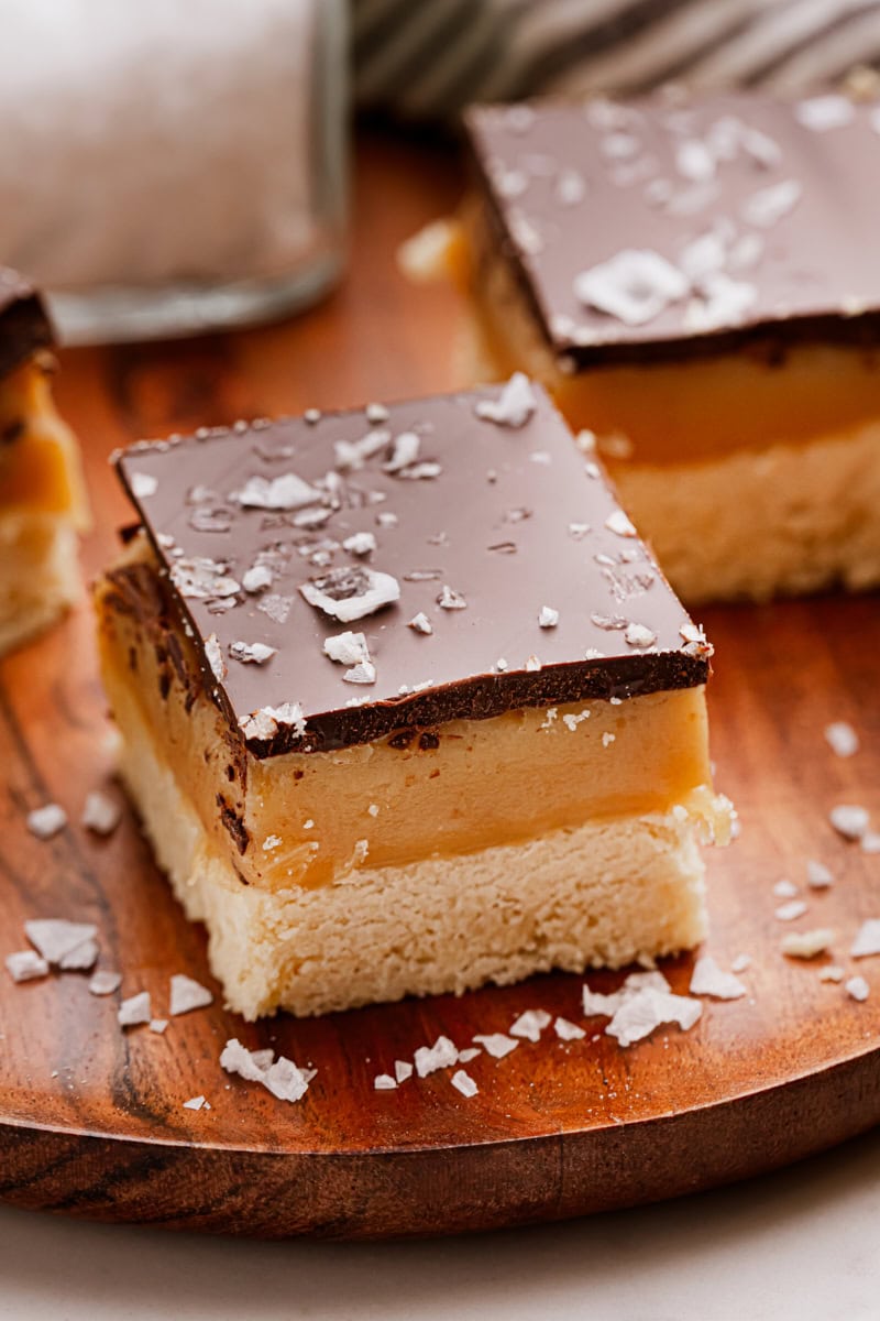 a millionaire shortbread bar on a wooden cutting board