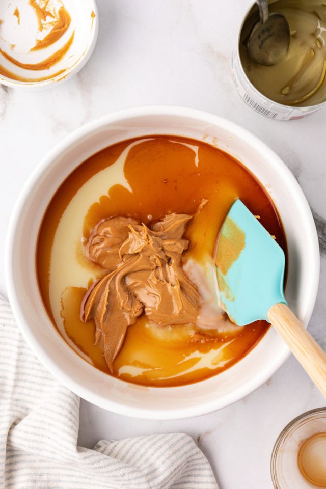 overhead view of condensed milk, peanut butter, and vanilla in a white bowl