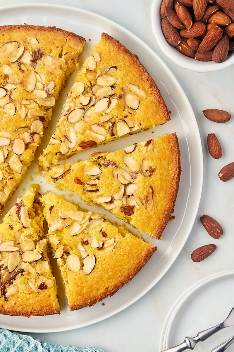 overhead view of partially sliced almond torte on a white cake plate