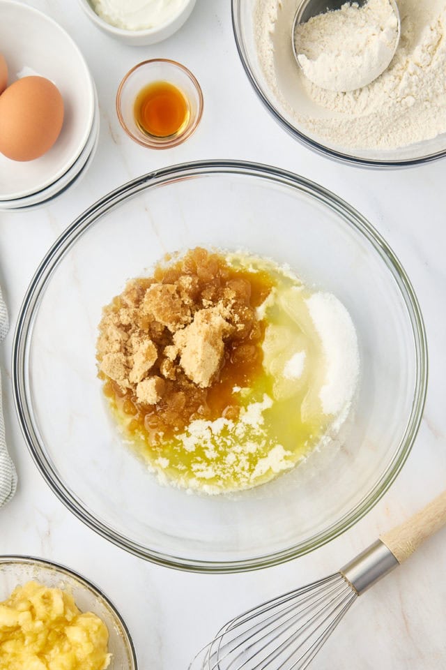 overhead view of melted butter, vegetable oil, brown sugar, and sugar in a glass mixing bowl