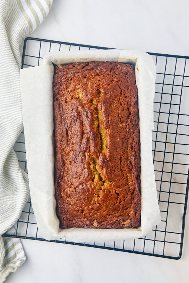 overhead view of freshly baked banana bread in a loaf pan on a wire rack