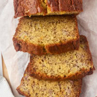 overhead view of partially sliced banana bread on parchment paper