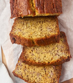 overhead view of partially sliced banana bread on parchment paper