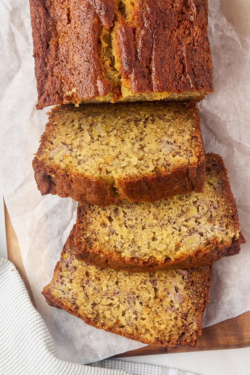 overhead view of partially sliced banana bread on parchment paper