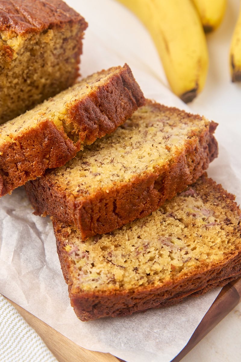 three slices of banana bread fanned out on a wooden cutting board