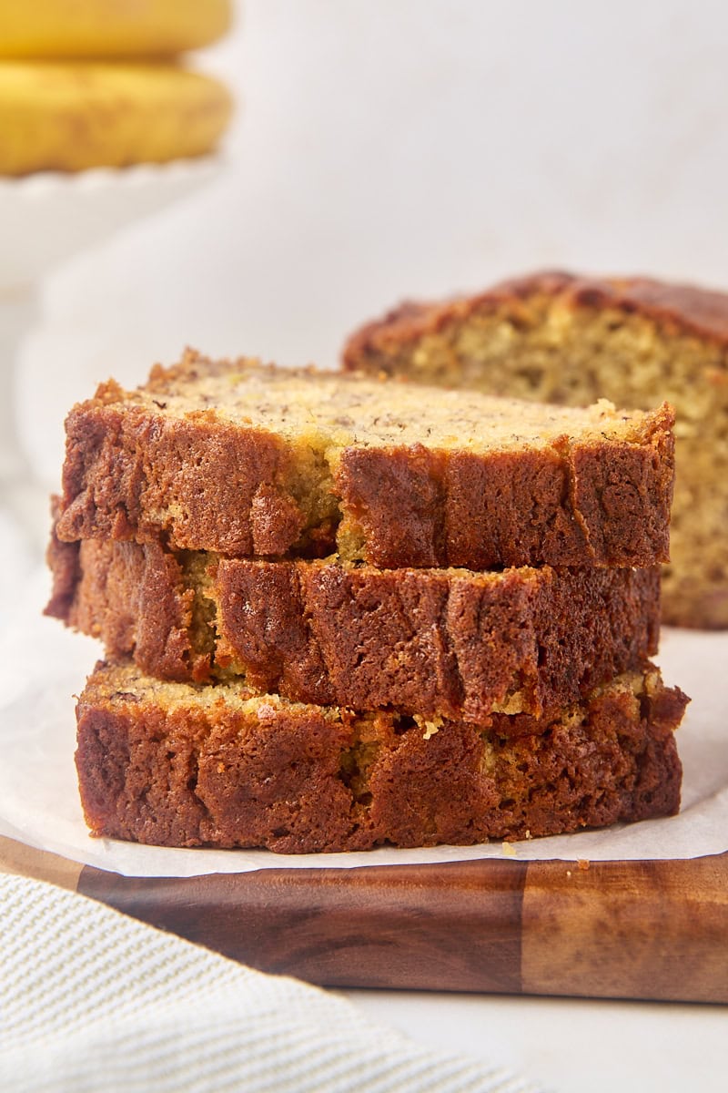 stack of three slices of banana bread with more bread in the background