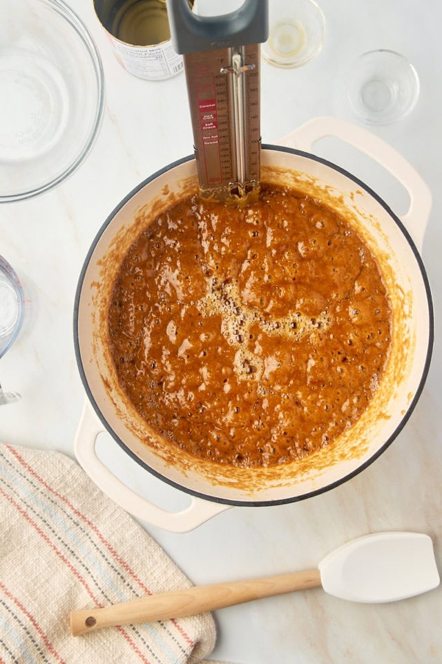 overhead view of caramel mixture in a large saucepan with a candy thermometer attached