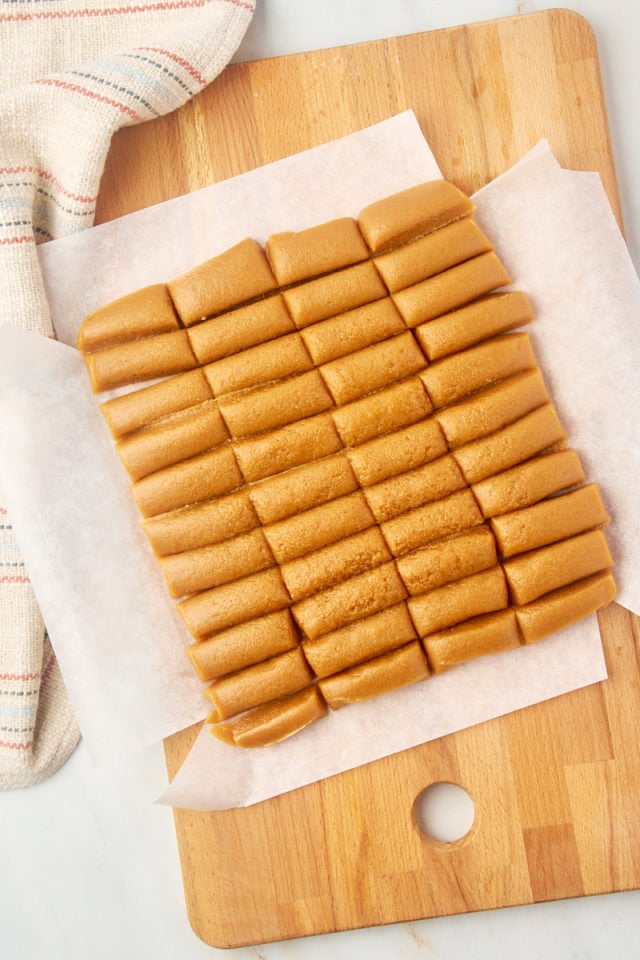 overhead view of caramel sliced into individual pieces on a wooden cutting board