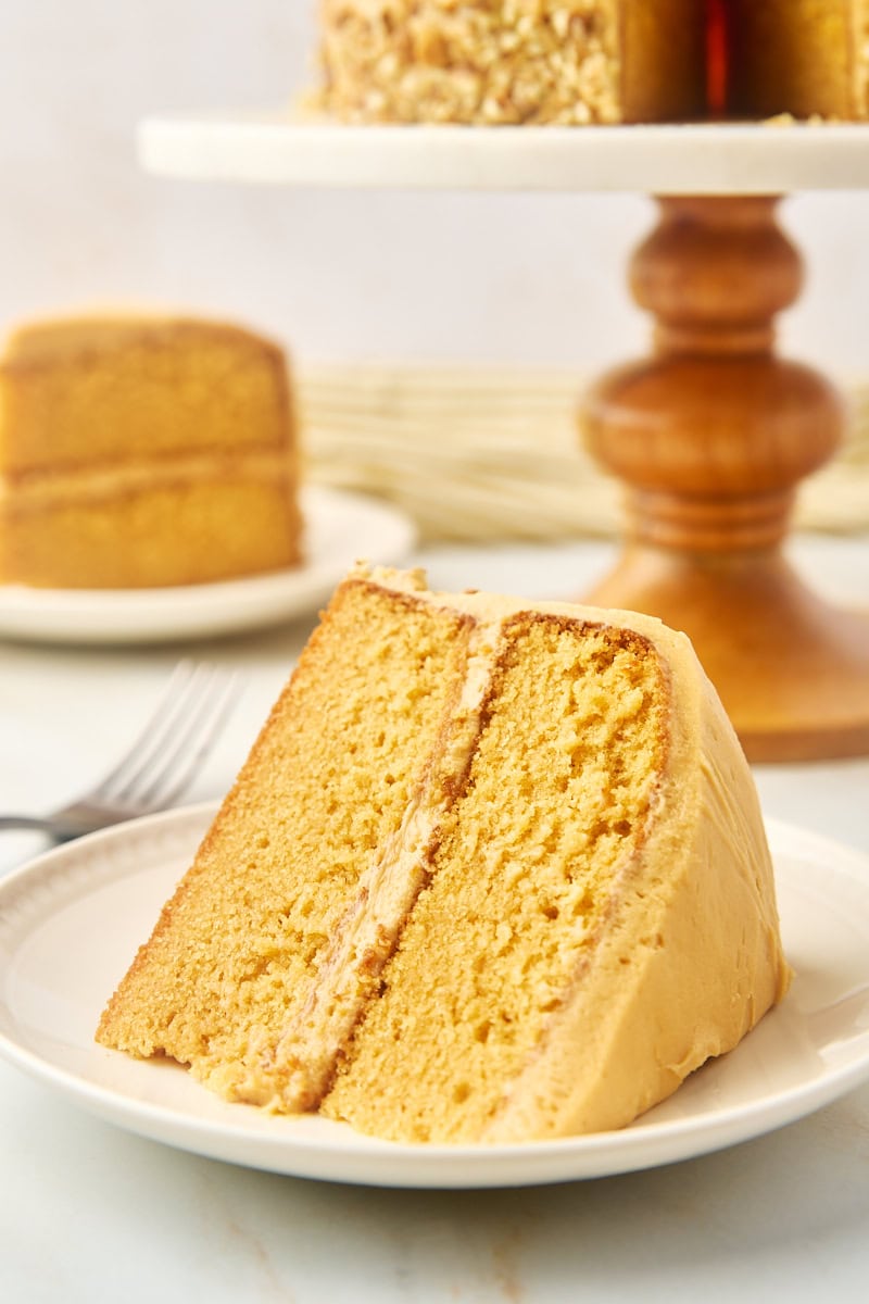 a slice of dulce de leche cake on a plate with more cake in the background