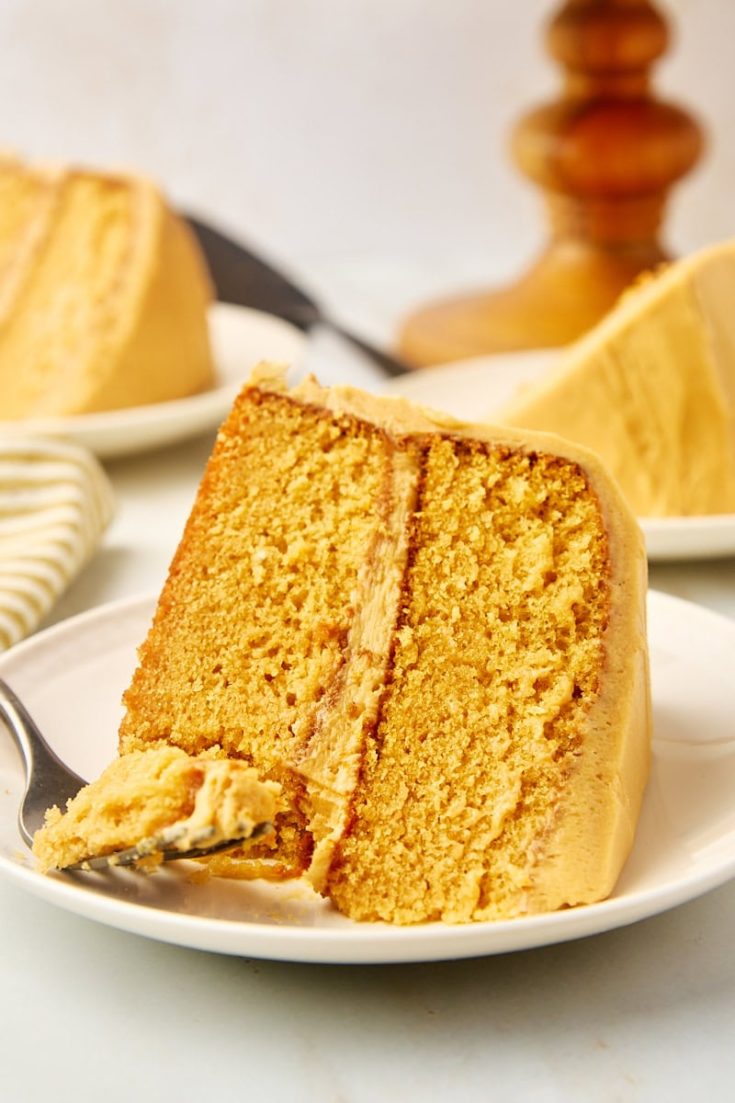 a slice of dulce de leche cake on a plate with a bite on a fork