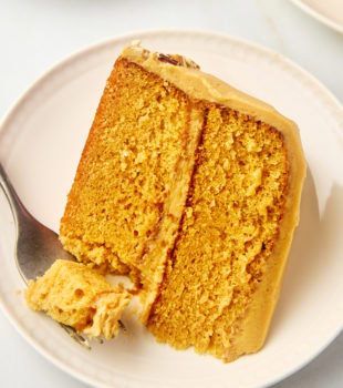 a slice of dulce de leche cake on a plate with a bite on a fork