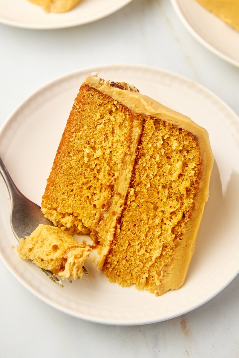 a slice of dulce de leche cake on a plate with a bite on a fork