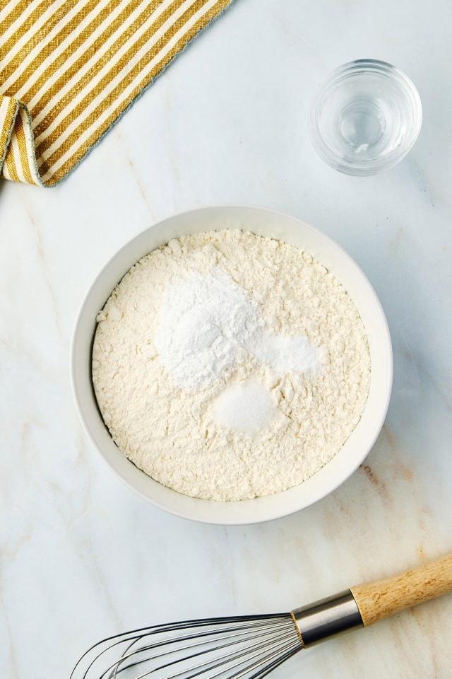 overhead view of flour, baking powder, baking soda, and salt in a white bowl