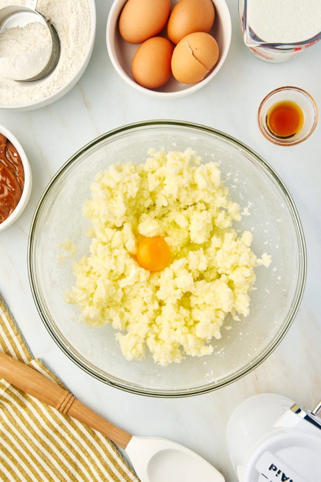 overhead view of egg added to creamed butter and sugar in a glass mixing bowl