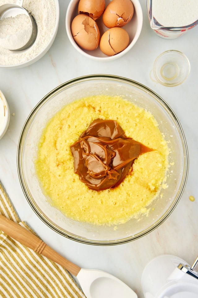 overhead view of dulce de leche and vanilla extract added to cake batter