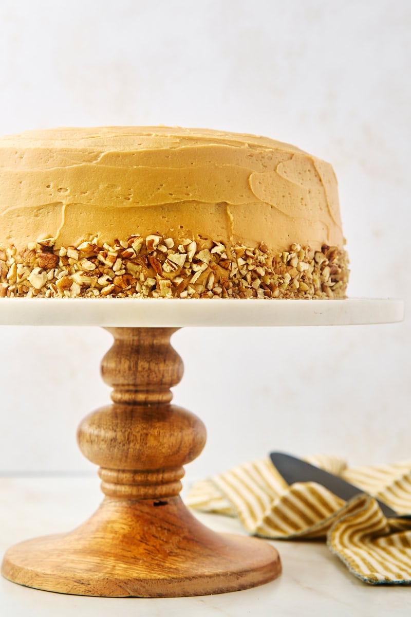 dulce de leche cake on a marble and wooden cake stand