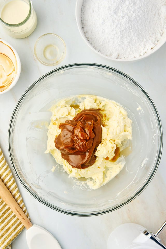 overhead view of dulce de leche and vanilla added to creamed butter in a glass mixing bowl