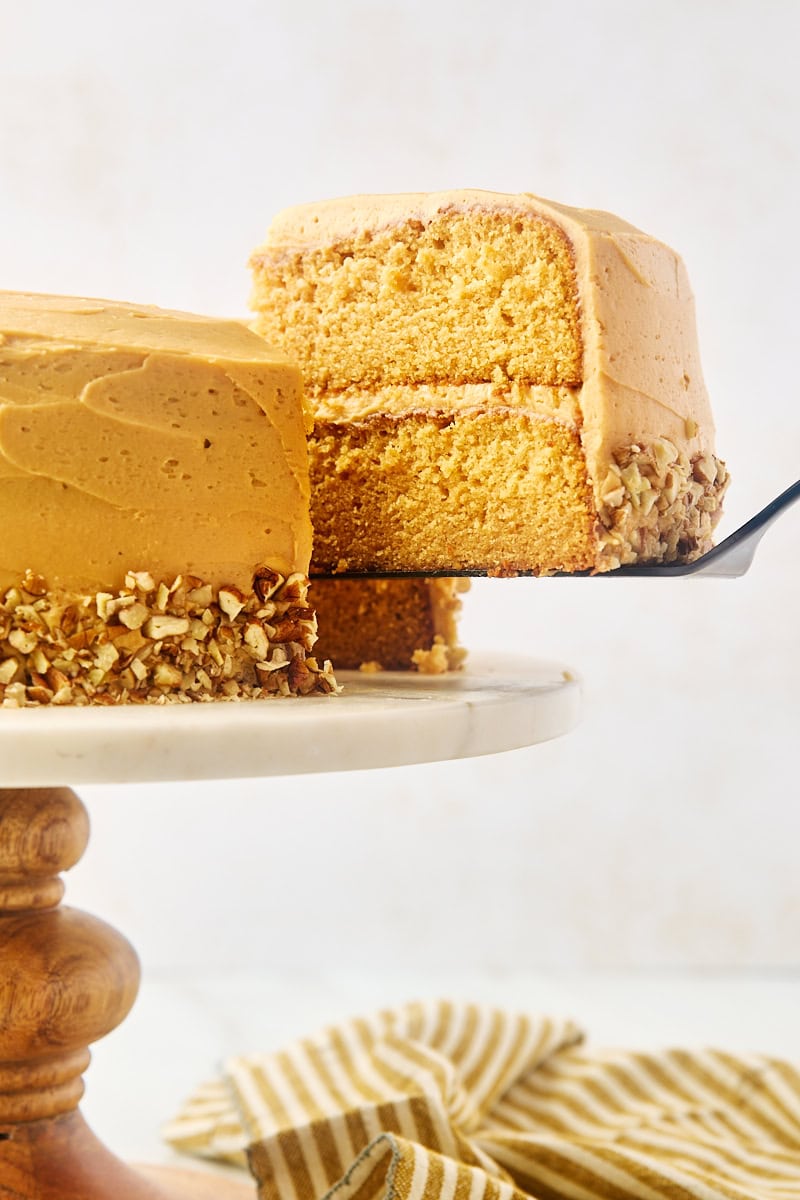 a slice of dulce de leche cake on a cake server being removed from the remaining cake