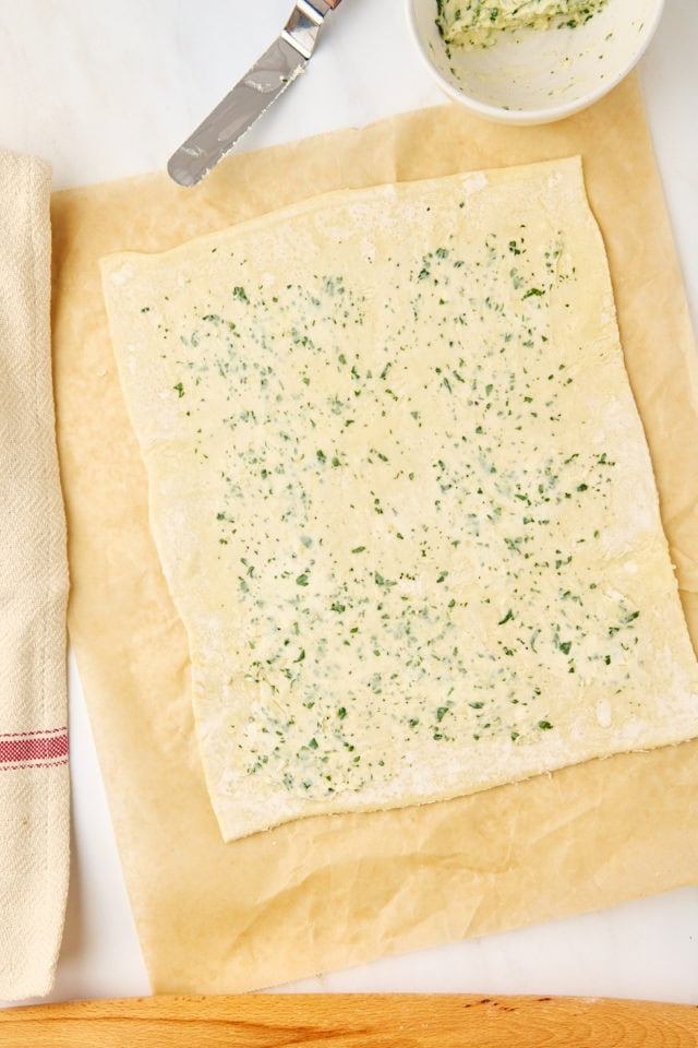 overhead view of garlic butter mixture spread on a sheet of puff pastry