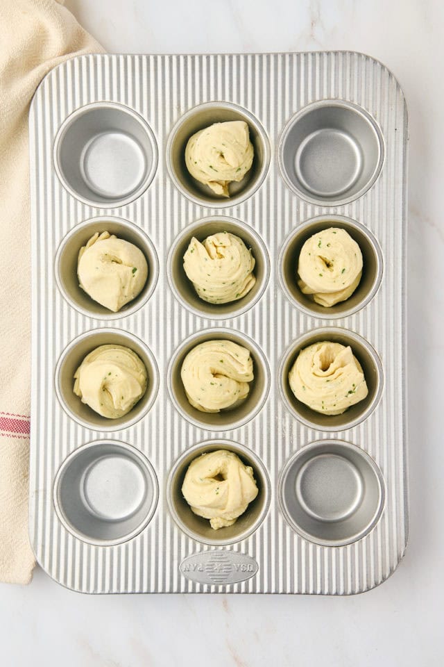 overhead view of garlic butter cruffins in a muffin pan ready to go into the oven