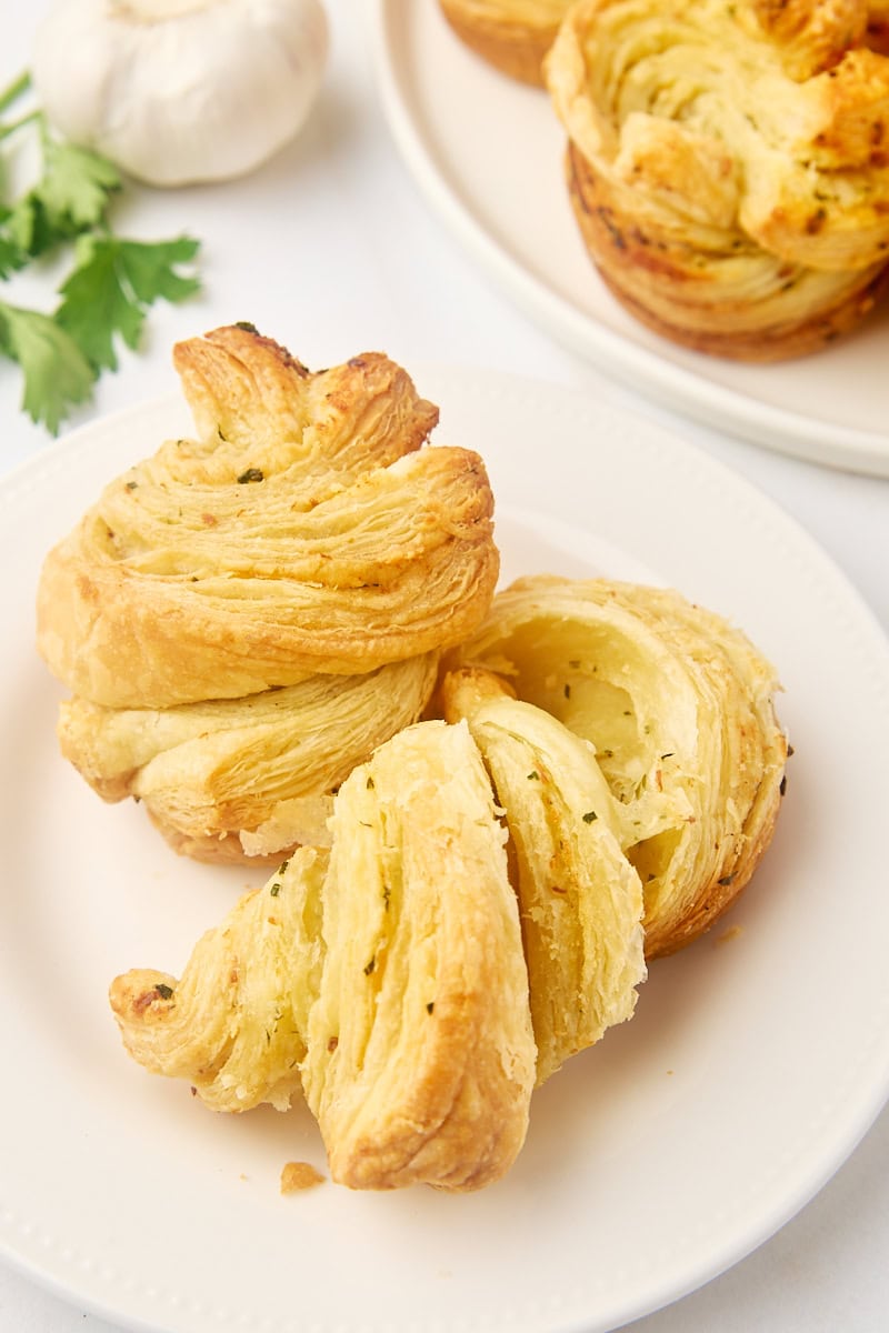 a pulled-apart garlic butter cruffin and another cruffin on a white plate