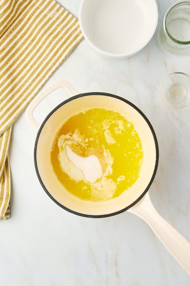 overhead view of sugar, water, and vanilla added to melted butter in a saucepan