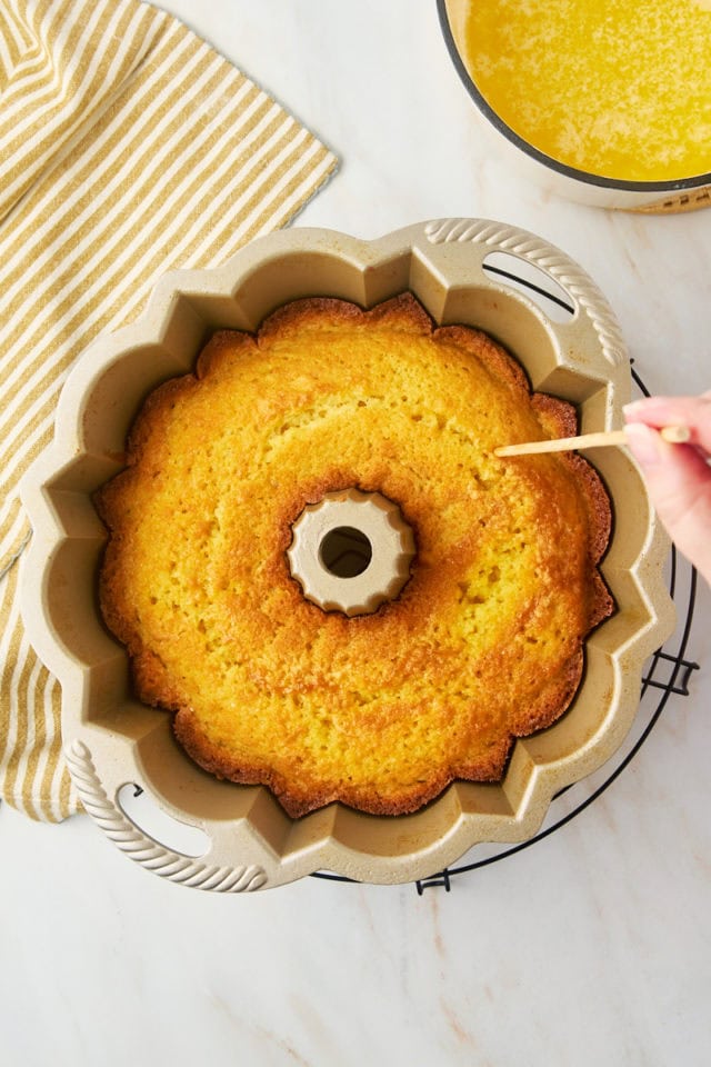 overhead view of holes being poked into warm Kentucky butter cake in a Bundt pan