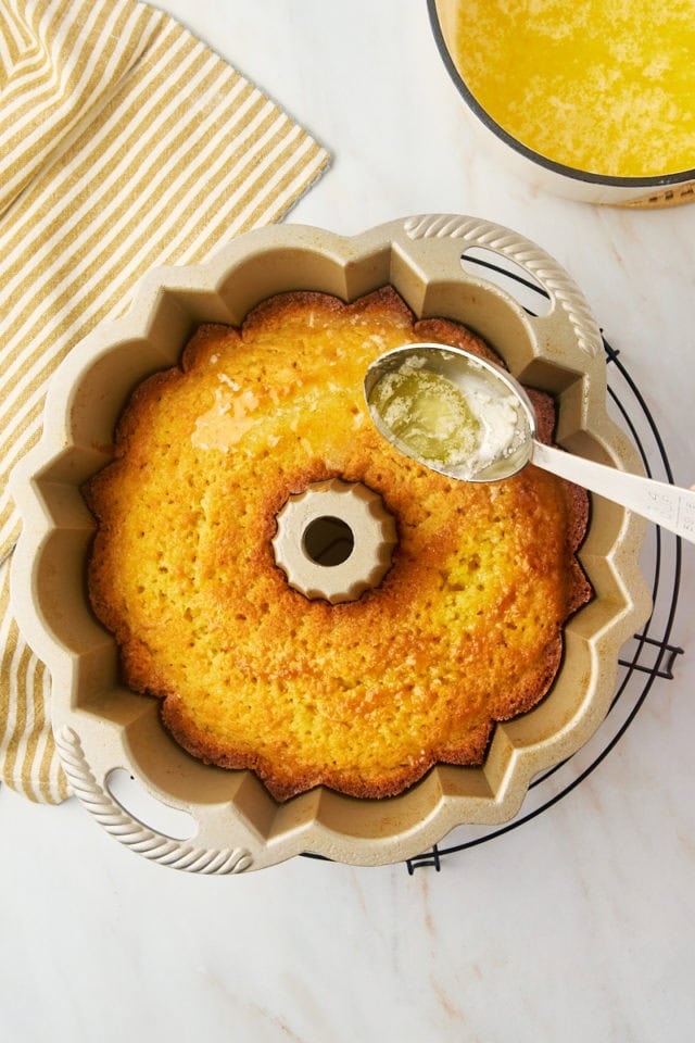 overhead view of butter glaze being spooned over warm Kentucky butter cake in a Bundt pan