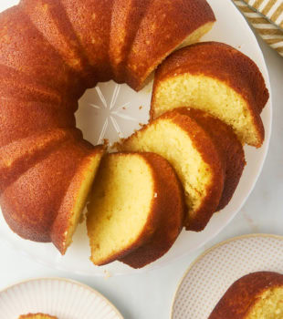 overhead view of partially sliced Kentucky butter cake on a cake stand with two more slices on plates alongside