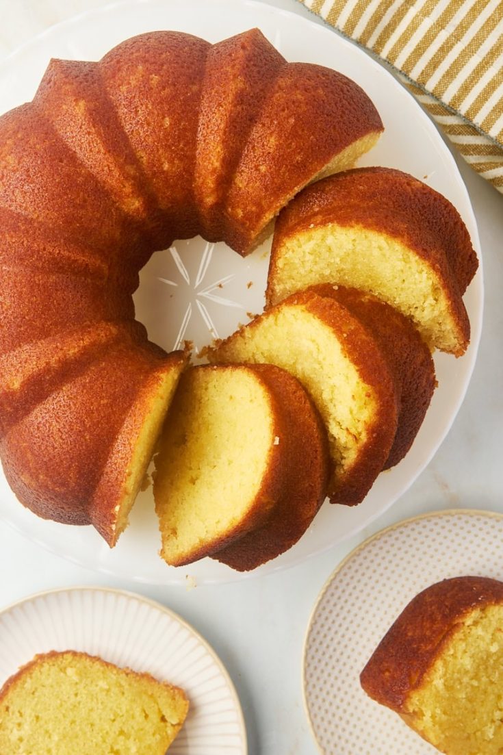 overhead view of partially sliced Kentucky butter cake on a cake stand with two more slices on plates alongside