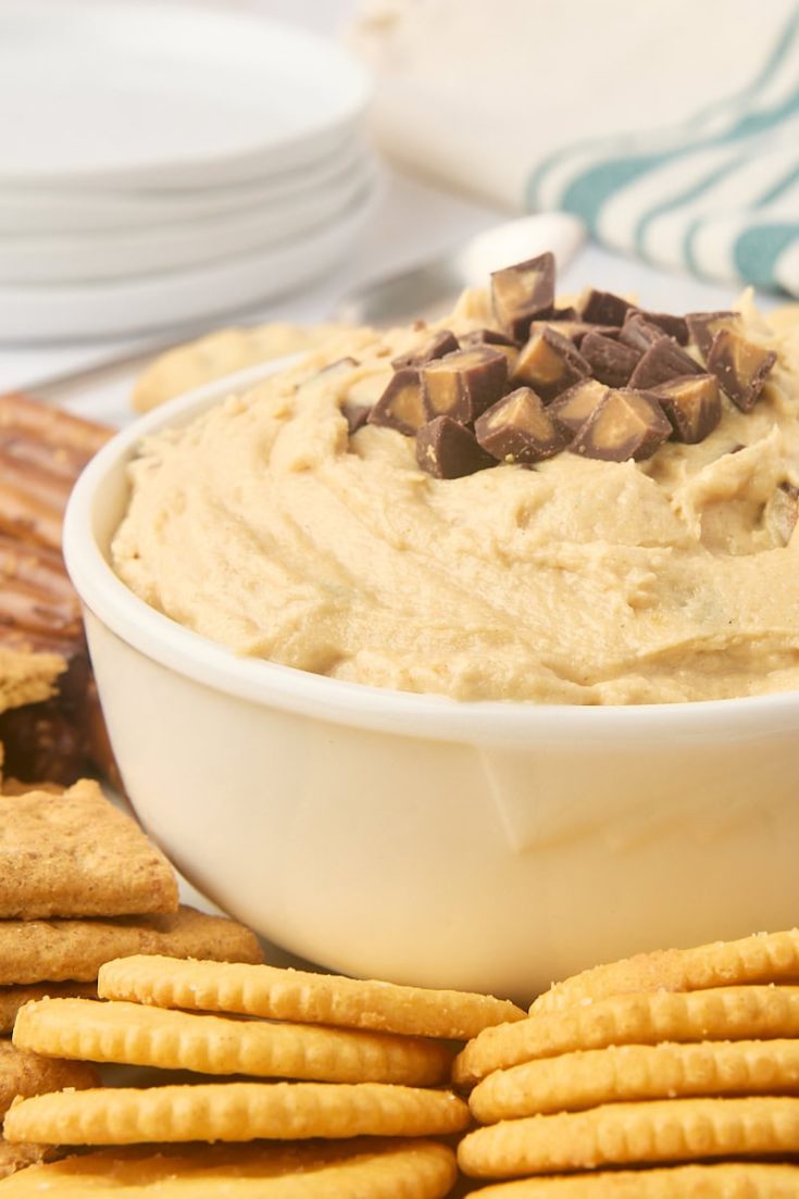 peanut butter cup dip in a white bowl with various dippers around the bowl