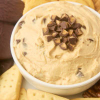 peanut butter cup dip in a white bowl served with cookies and crackers beside the bowl