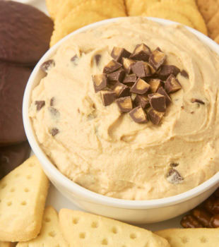 peanut butter cup dip in a white bowl served with cookies and crackers beside the bowl