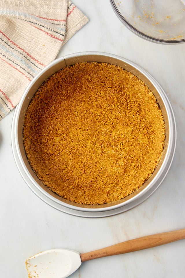 overhead view of graham cracker crust pressed into a springform pan