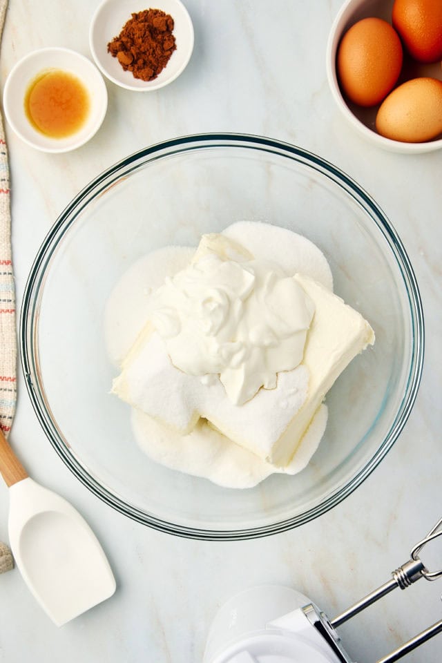 overhead view of cream cheese, sugar, and sour cream in a glass mixing bowl