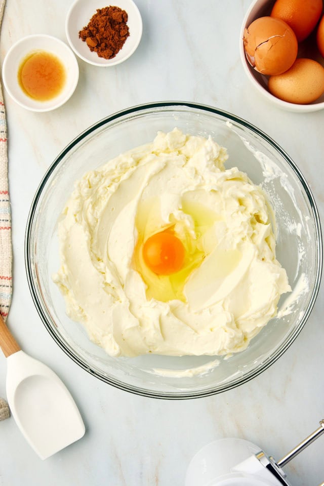 overhead view of egg added to snickerdoodle cheesecake filling mixture