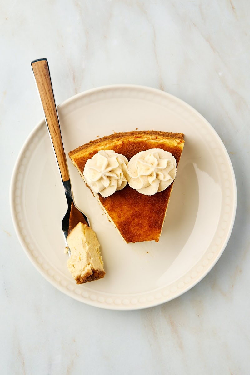 a slice of snickerdoodle cheesecake on a plate with a bite on a fork