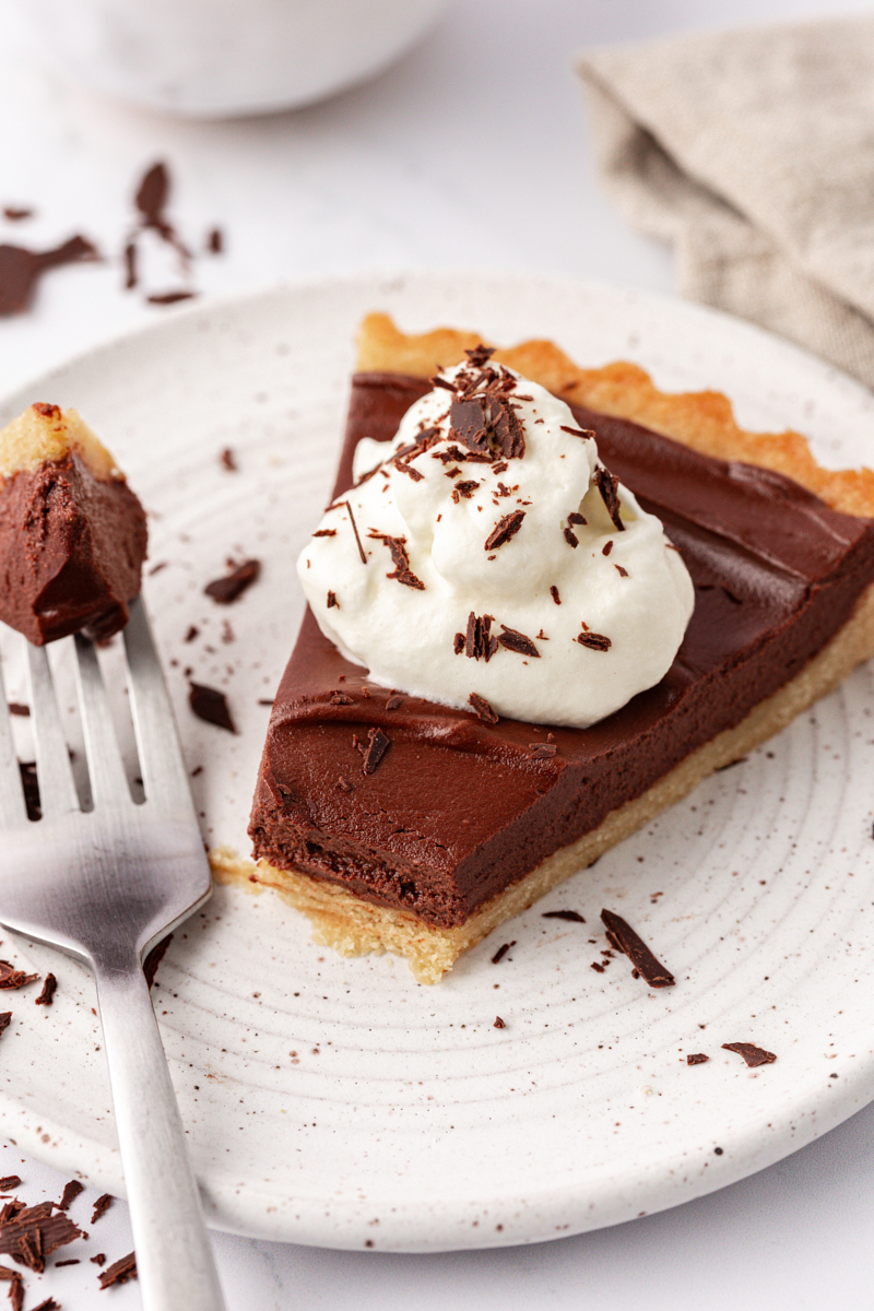 slice of chocolate mascarpone tart on a plate with a bite on a fork