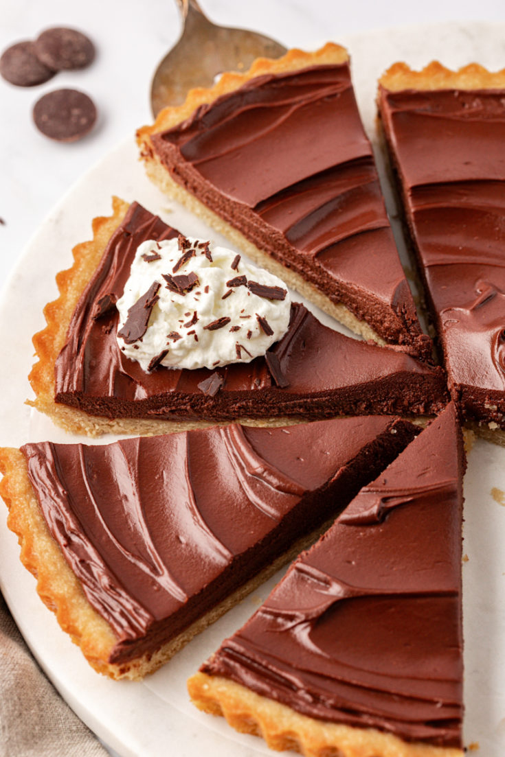 partially sliced chocolate mascarpone tart on a white cake plate