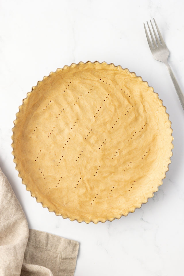 overhead view of tart crust dough pressed into a tart pan and docked with a fork