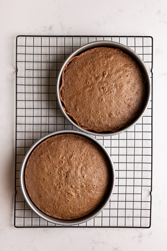 Two baked German chocolate cake layers in pans on wire rack