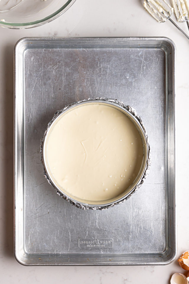 Cheesecake batter in springform pan on sheet pan