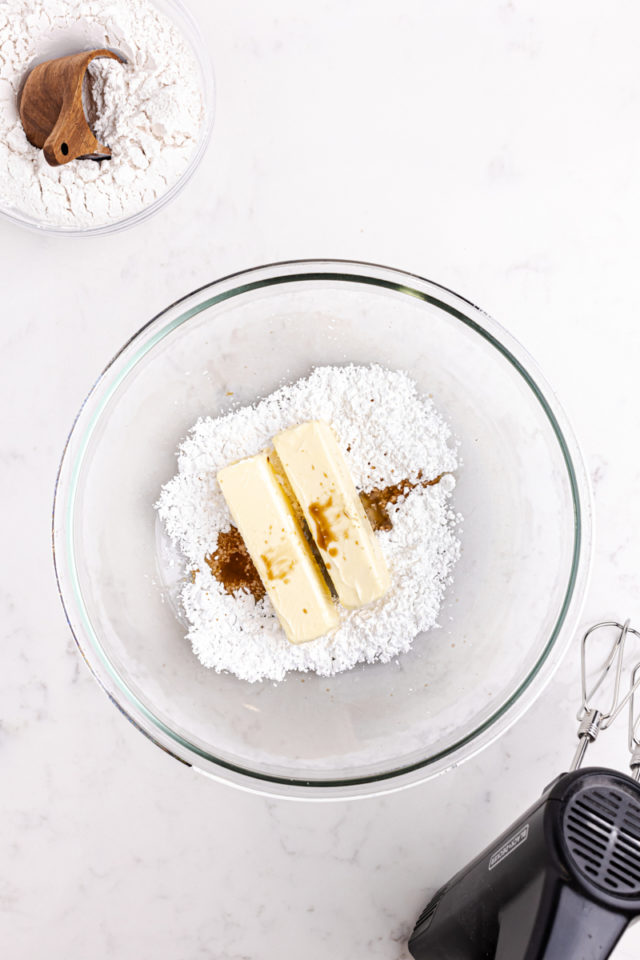 overhead view of butter, confectioners' sugar, and vanilla extract in a mixing bowl